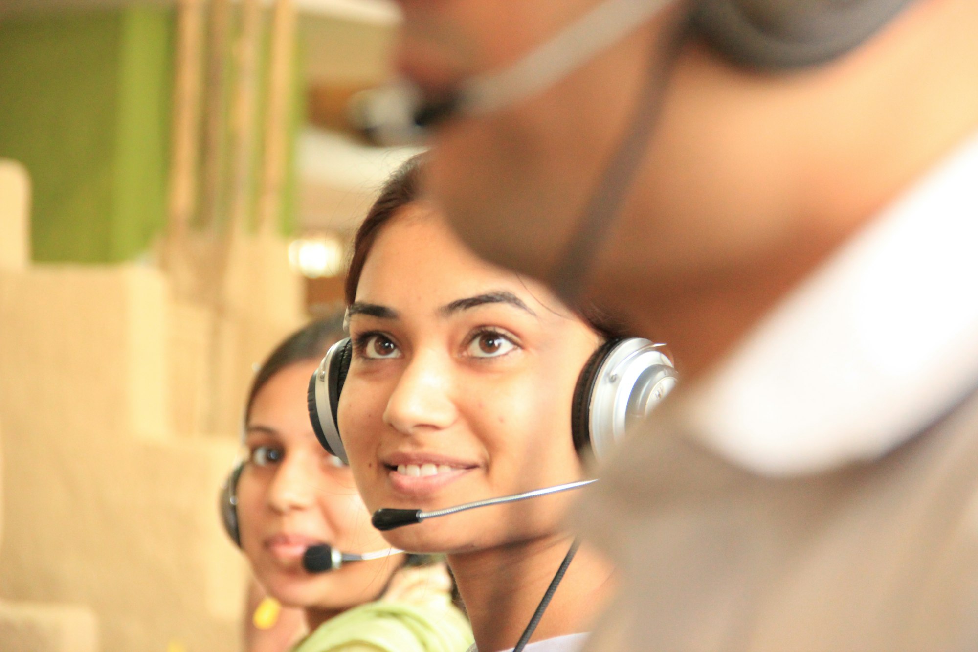 Two customer service staff wearing headsets in a bright office