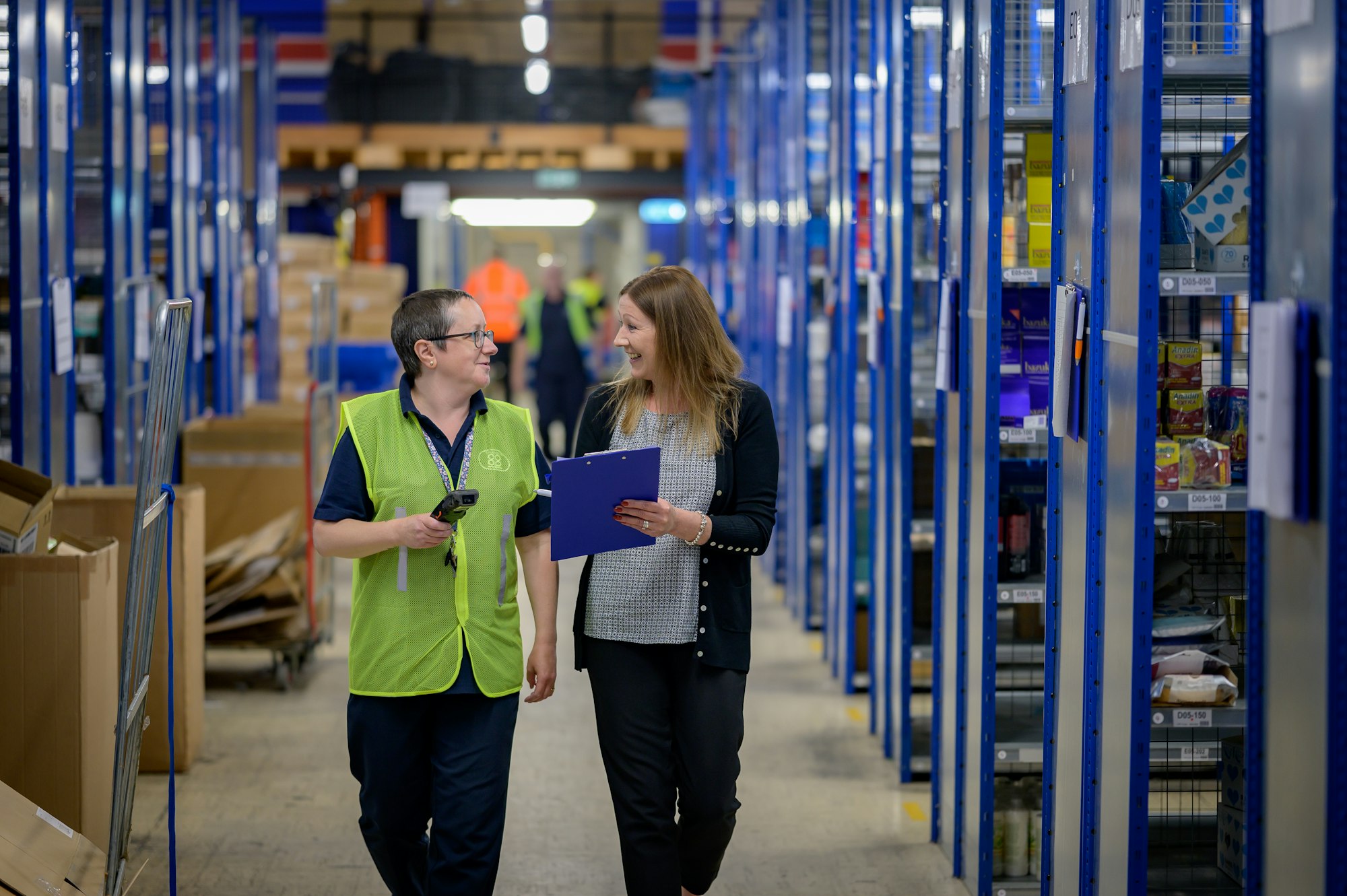 Two staff walking through a warehouse aisle